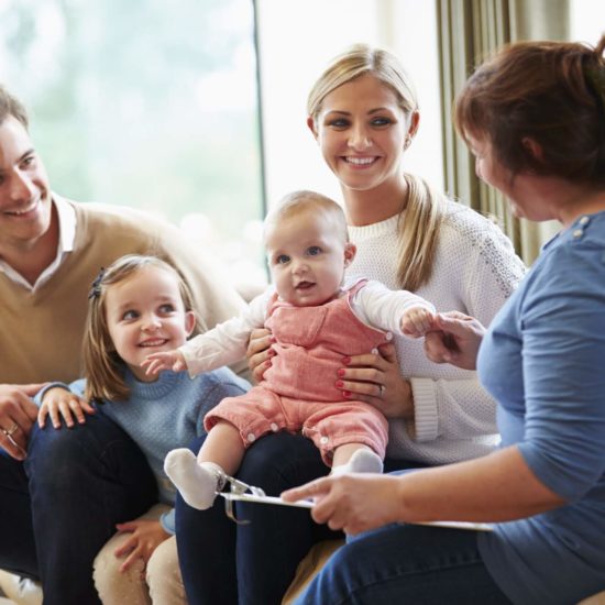 Health Visitor Talking To Happy Smiling Family With Young Baby